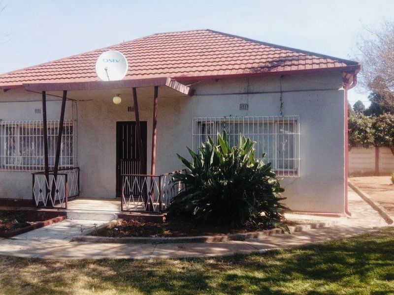 Front elevation of a single-story house featuring a tiled roof, covered porch entrance, and security bars on windows.