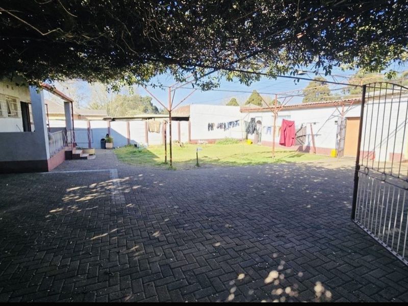 Spacious rear courtyard featuring paved flooring, perimeter walling, and a metal clothesline structure, providing a functional outdoor utility area.