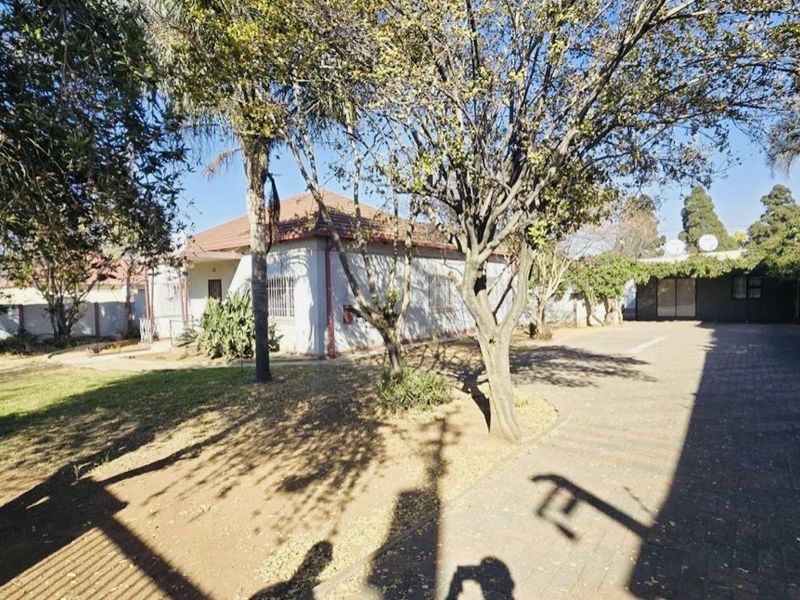 Front view of a residential property featuring a paved driveway, tiled roof, and established garden area.