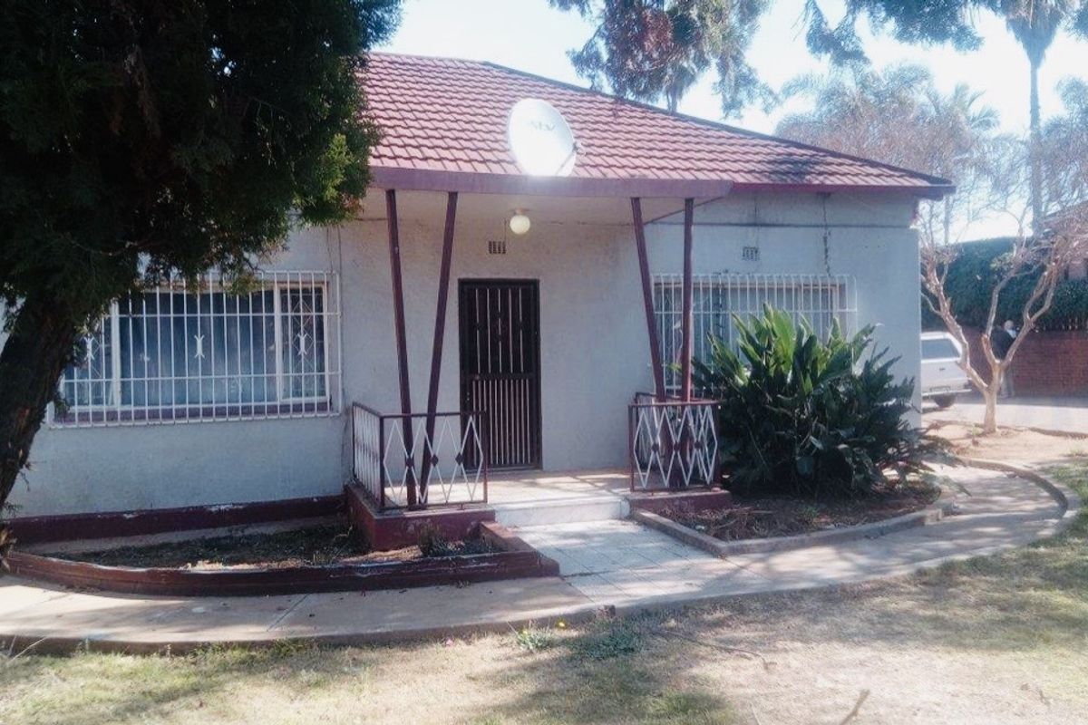 Front elevation of a single-story house featuring a covered porch, security bars on windows, and a tiled roof.