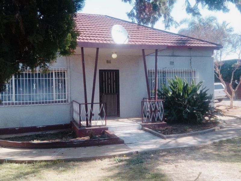 Front elevation of a single-story house featuring a covered porch, security bars on windows, and a tiled roof.