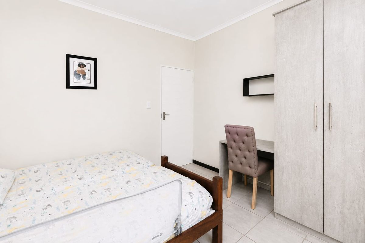 A well-maintained bedroom featuring neutral walls, tiled flooring, and a practical built-in wardrobe for storage.