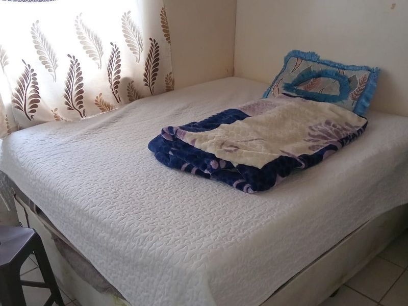 A compact bedroom featuring tiled flooring and neutral wall finishes, suitable for a single bed setup.