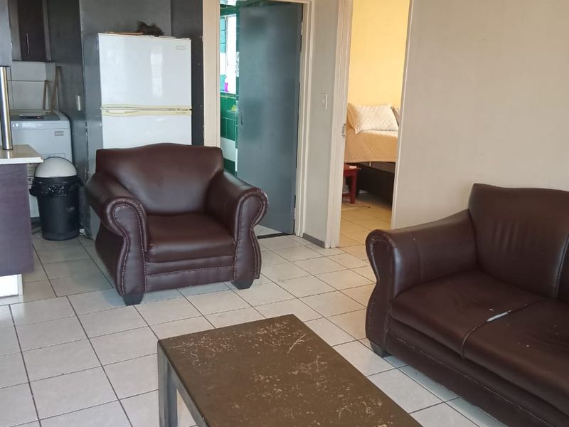 Open plan living area featuring tiled flooring and direct access to adjacent rooms, offering a functional layout with potential for cosmetic updates.