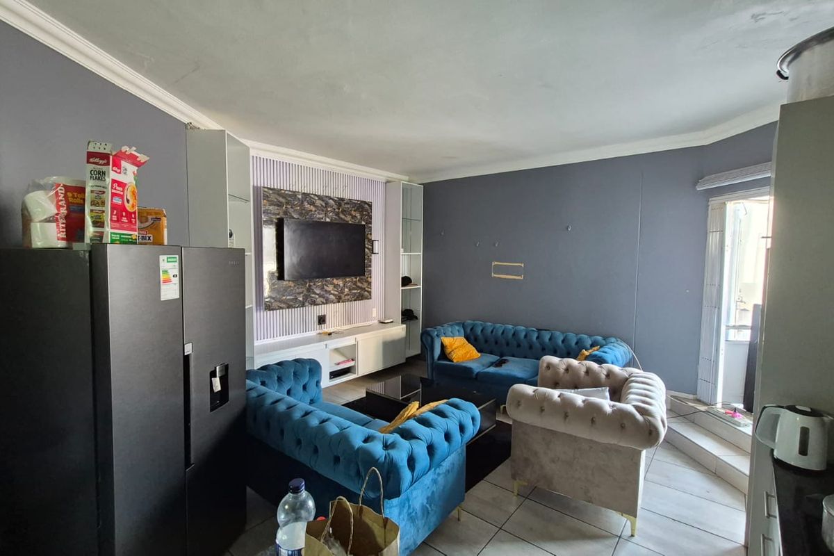 Open-plan living area featuring tiled flooring, a built-in media unit, and access to an outdoor balcony space.