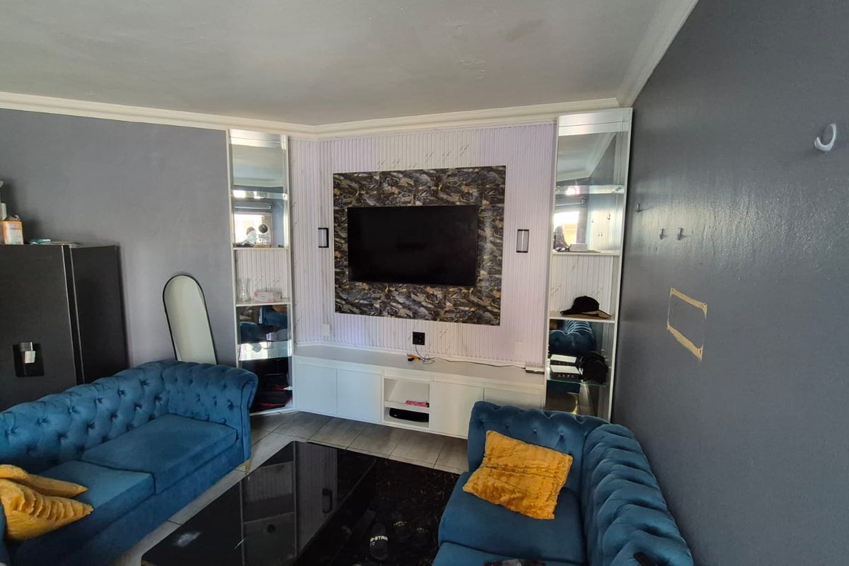 Living room featuring a built-in media unit with integrated mirrored shelving and tiled flooring.