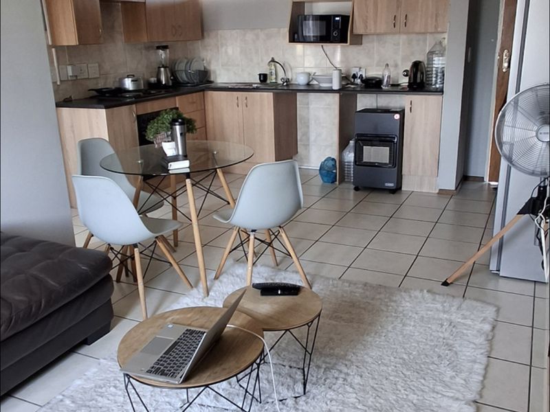 Open plan living and kitchen area featuring tiled flooring, light wood-tone cabinetry, and a functional layout suitable for modern apartment living.
