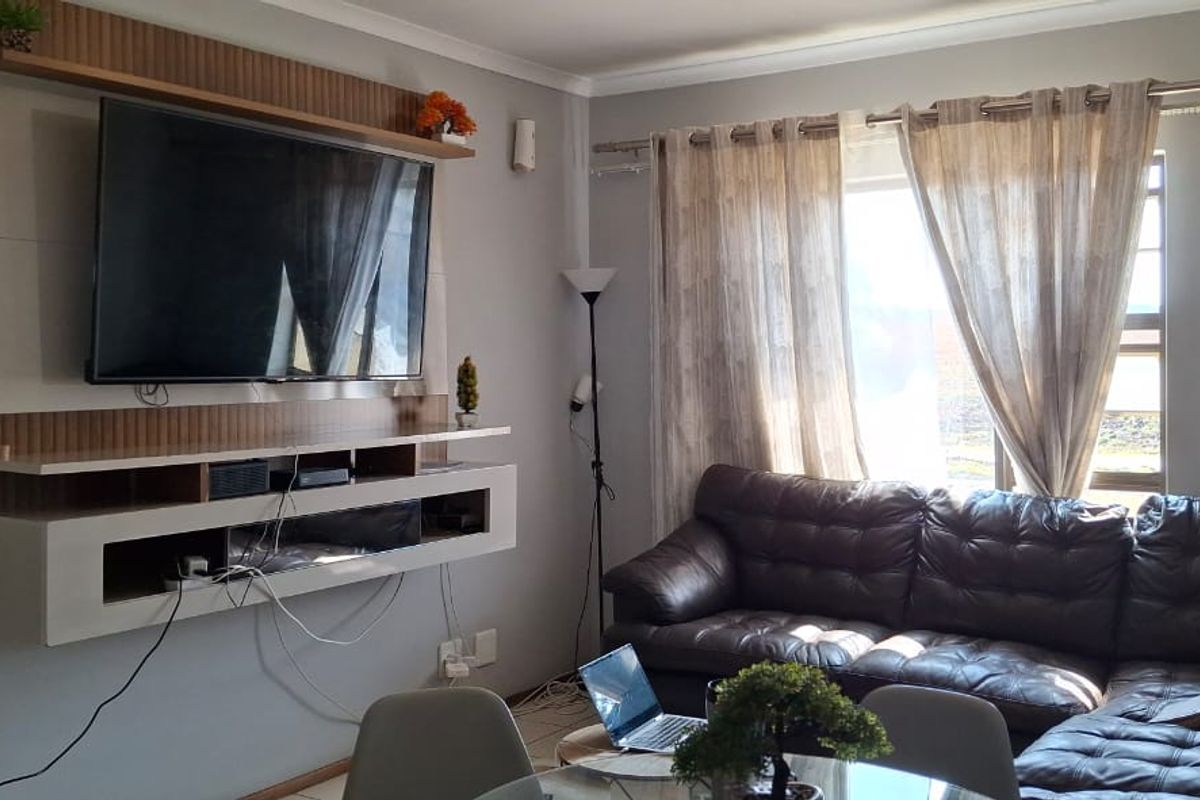 A comfortable living room featuring a modern built-in media unit and tiled flooring, offering a functional space for relaxation.