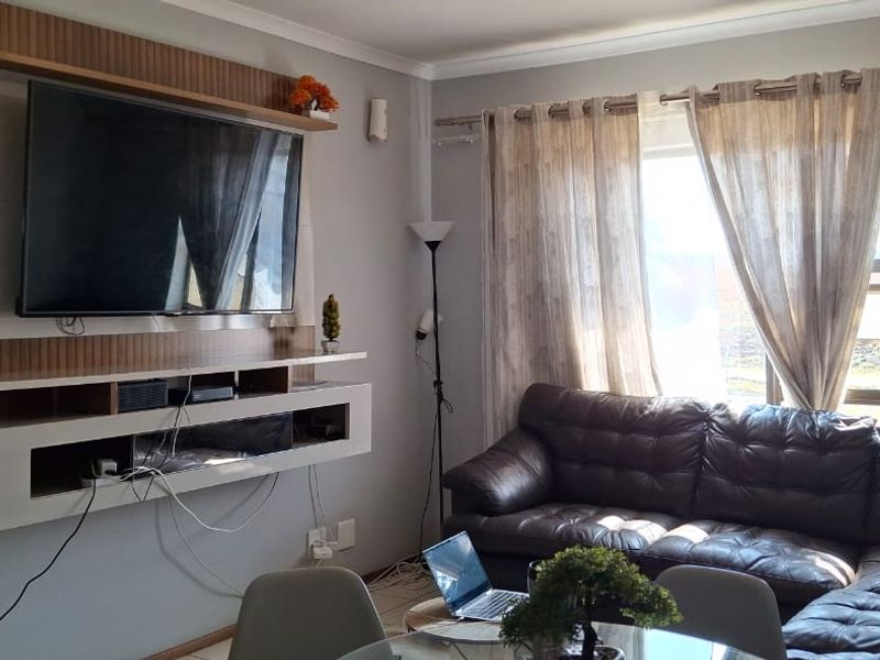 A comfortable living room featuring a modern built-in media unit and tiled flooring, offering a functional space for relaxation.