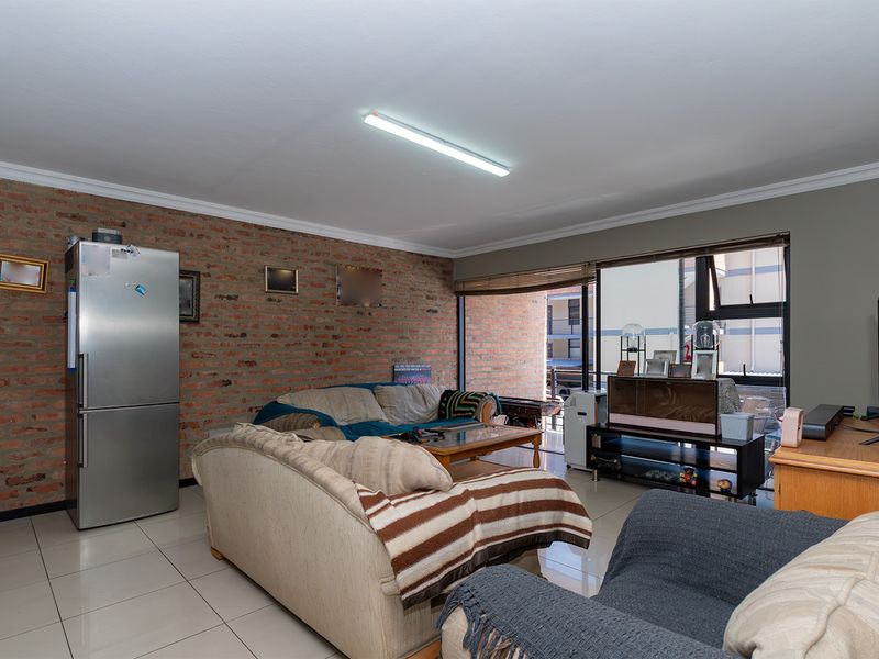 A living room featuring an exposed brick feature wall, tiled flooring, and large sliding glass doors providing access to the exterior.