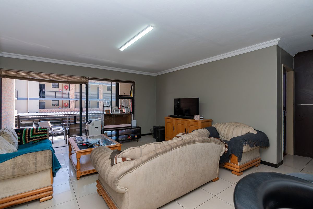 A living room featuring tiled flooring, a large sliding glass door providing natural light, and neutral wall finishes.