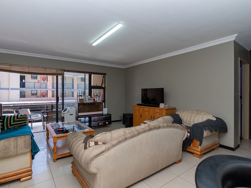 A living room featuring tiled flooring, a large sliding glass door providing natural light, and neutral wall finishes.
