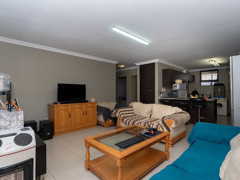 Open-plan living area featuring tiled flooring and a functional kitchen with built-in cabinetry and a breakfast island.