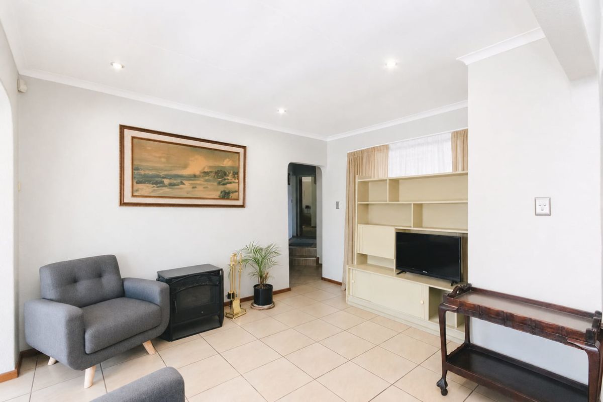 A bright living room featuring tiled flooring, a built-in fireplace, and a custom shelving unit, offering a clean and functional space.