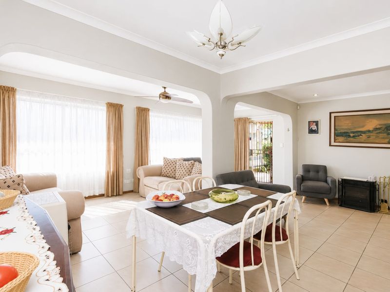 Spacious open-plan living and dining area featuring neutral tiled flooring, arched architectural details, and a built-in fireplace, creating a bright and inviting atmosphere.