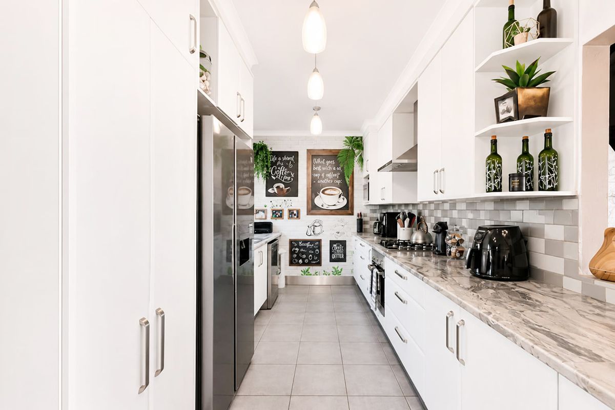 Modern galley-style kitchen featuring white cabinetry, stone-look countertops, gas cooktop, built-in oven, and stylish tiled backsplash with contemporary pendant lighting.
