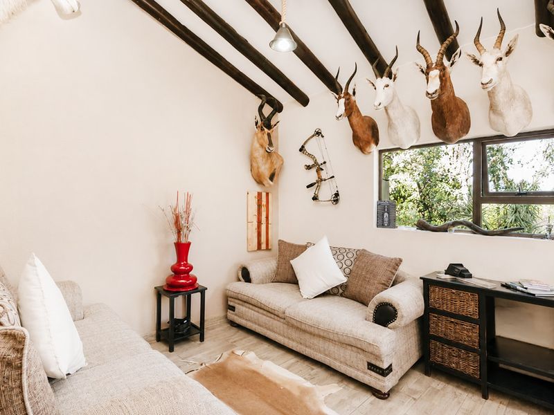 A cozy living room featuring exposed timber ceiling beams, tiled flooring, and a large window providing natural light.