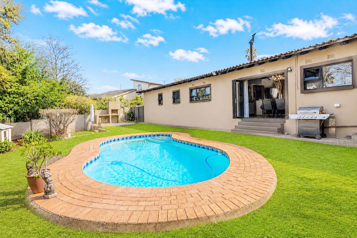 Rear garden featuring a swimming pool with brick coping, a built-in braai, and direct access to the home via bi-fold doors.
