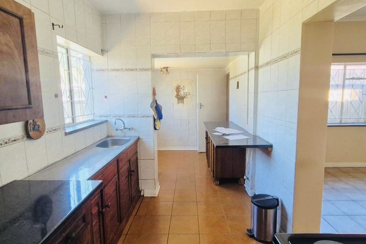 A dated kitchen featuring built-in wooden cabinetry, tiled walls, and tiled flooring, offering a functional layout with potential for modern renovation.