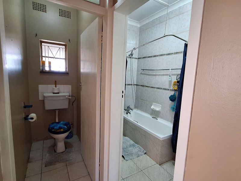 A functional bathroom featuring a separate toilet area and a combined bathtub and shower setup with tiled finishes.