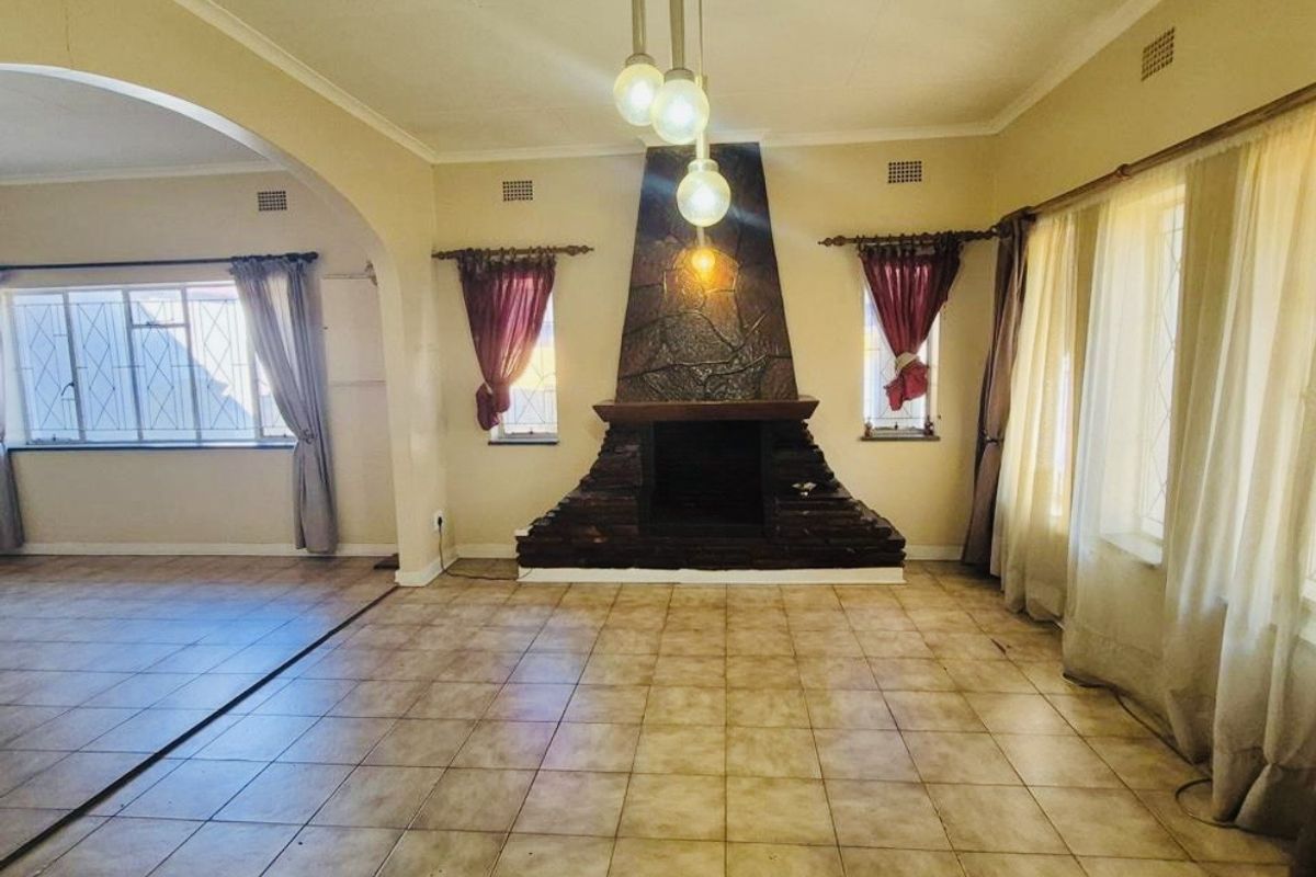 Spacious living room featuring a prominent stone fireplace, tiled flooring, and an open archway leading to an adjacent area.