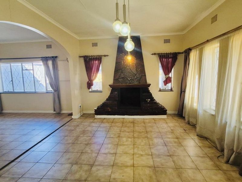 Spacious living room featuring a prominent stone fireplace, tiled flooring, and an open archway leading to an adjacent area.
