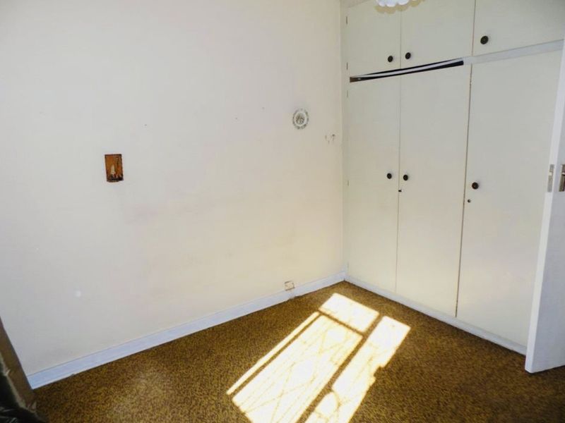 An empty bedroom featuring built-in cupboards and original flooring, offering a blank canvas for renovation and modernization.