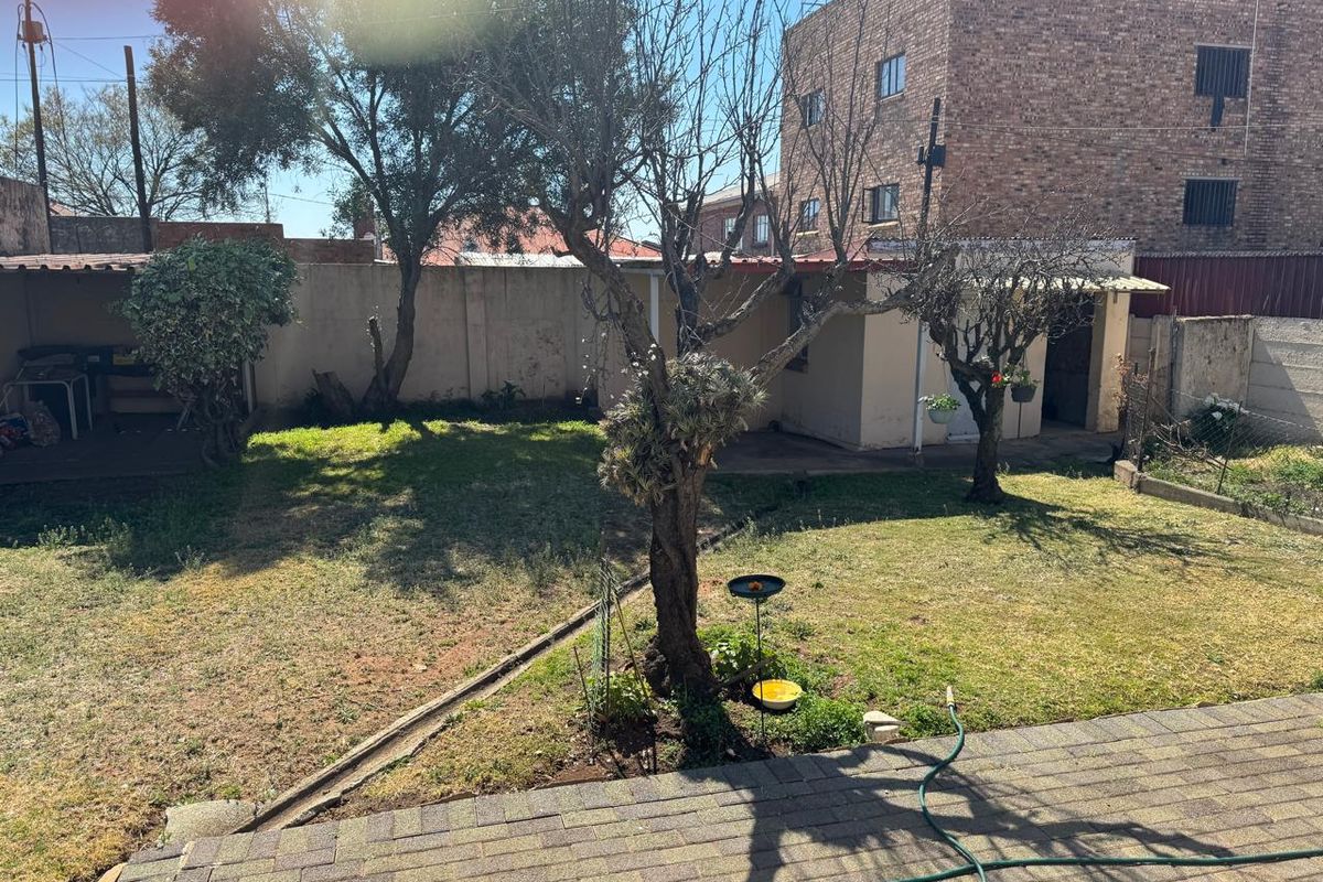 A rear garden area featuring a paved patio, lawn, and perimeter walling, providing an outdoor space for potential landscaping.