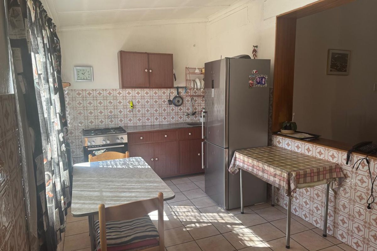 A functional kitchen featuring tiled flooring, a decorative tiled backsplash, built-in cabinetry, and a gas stove, offering potential for modernization.