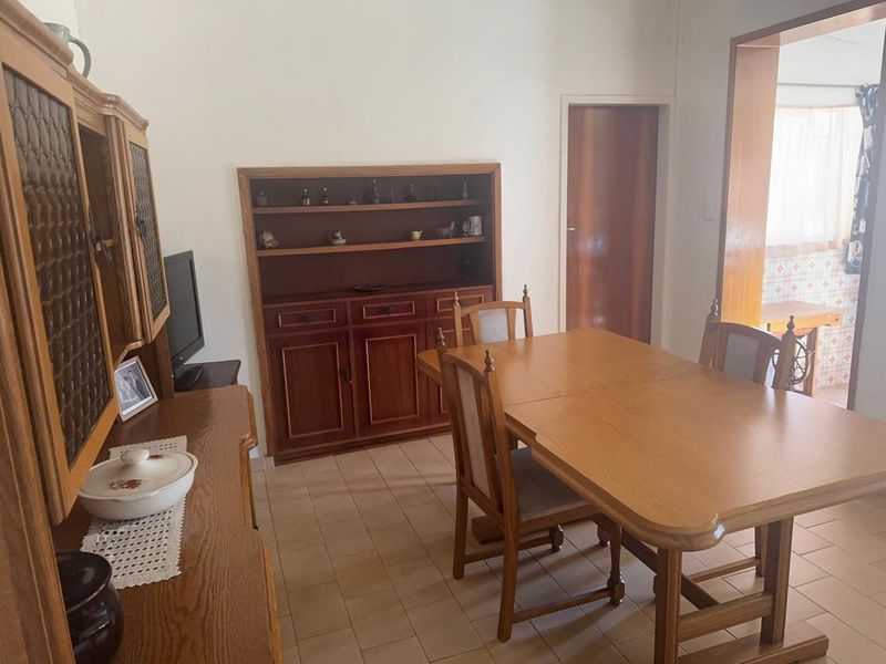 A dining room featuring tiled flooring and built-in wooden cabinetry, with an open transition leading into the adjacent kitchen area.