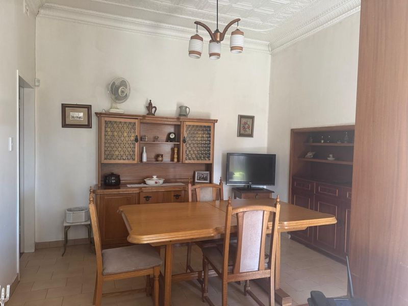 A dining room featuring tiled flooring, ornate ceiling cornicing, and built-in wooden cabinetry, offering a traditional aesthetic with potential for modern updates.