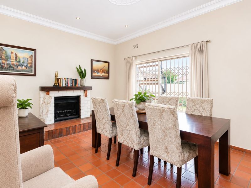 A dining room featuring terracotta floor tiles, a brick fireplace, and ceiling cornice, providing a warm and traditional atmosphere.
