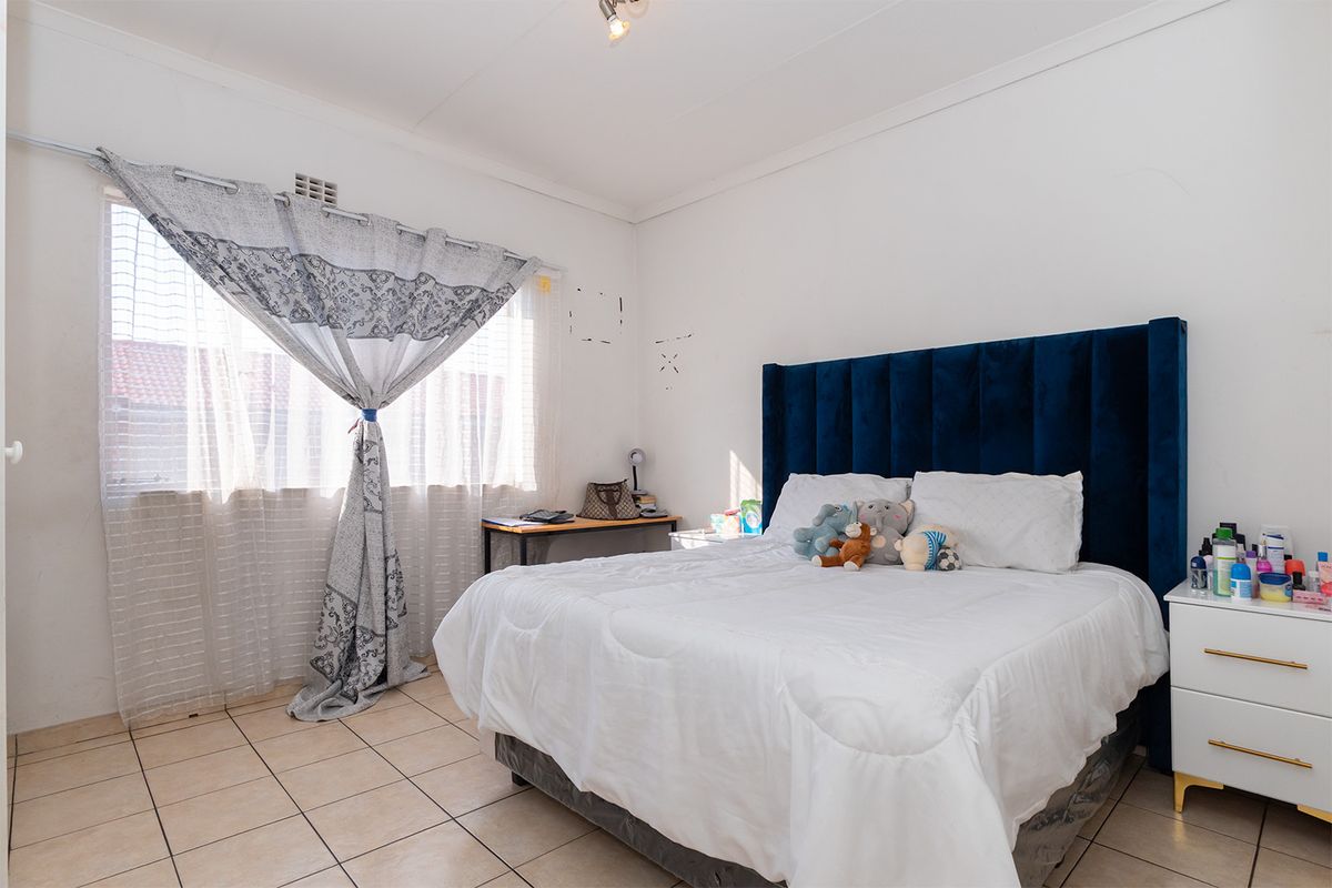 A bedroom featuring tiled flooring and a window, providing a functional space with neutral walls ready for personalization.