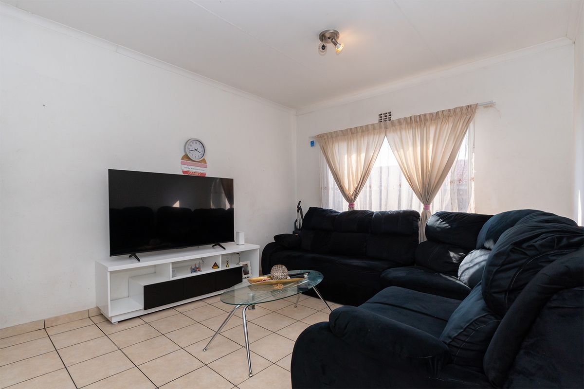 A functional living room featuring neutral tiled flooring and a window with installed curtain rods, providing a blank canvas for interior updates.