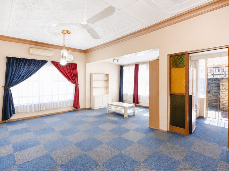 Spacious living area featuring a decorative pressed metal ceiling, ceiling fan, split system air conditioning, and a unique stained glass door entry.