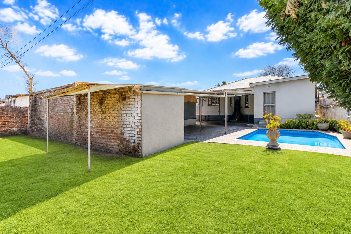 Rear garden area featuring a swimming pool, paved surround, and a detached brick outbuilding with a covered patio area.