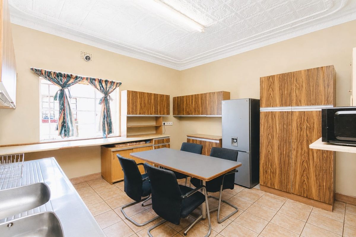 A functional kitchen featuring wood-look cabinetry, tiled flooring, and a double sink, offering a practical layout with potential for modern updates.