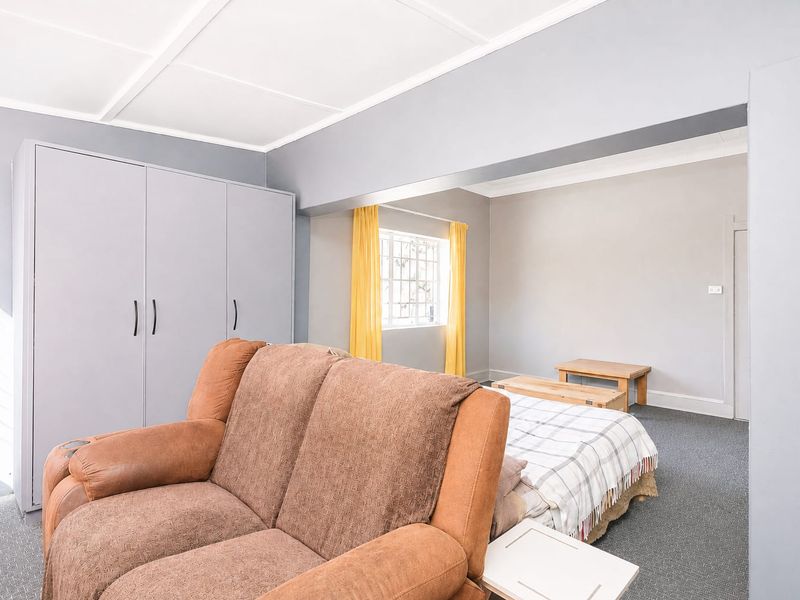 A bedroom featuring built-in wardrobes, carpeted flooring, and a grid ceiling, offering a functional layout with neutral wall tones.