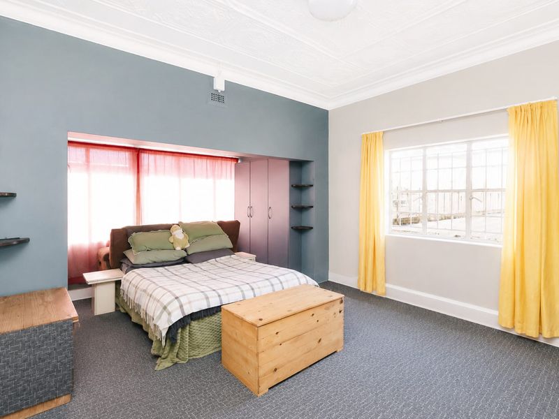 Spacious bedroom featuring built-in cupboards, decorative ceiling detailing, and large windows that provide ample natural light.
