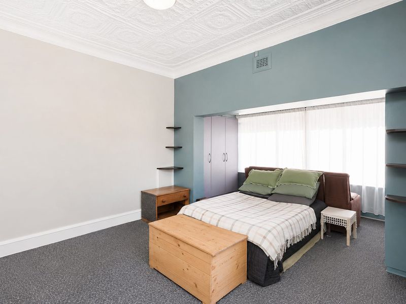 Spacious bedroom featuring a decorative ceiling, built-in wardrobe, and floating shelving, offering a comfortable and functional living space.