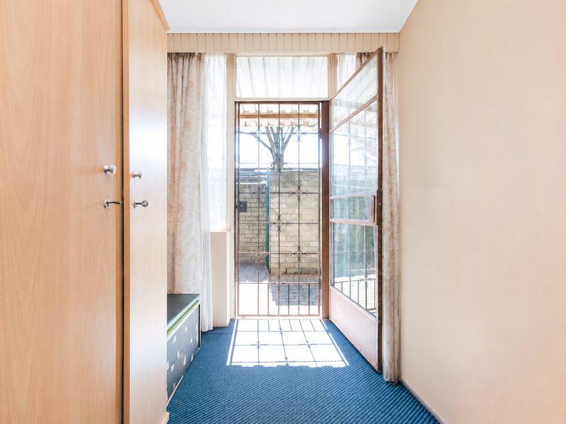 Entrance area featuring a security gate, built-in storage cupboard, and carpeted flooring, providing direct access to the exterior.