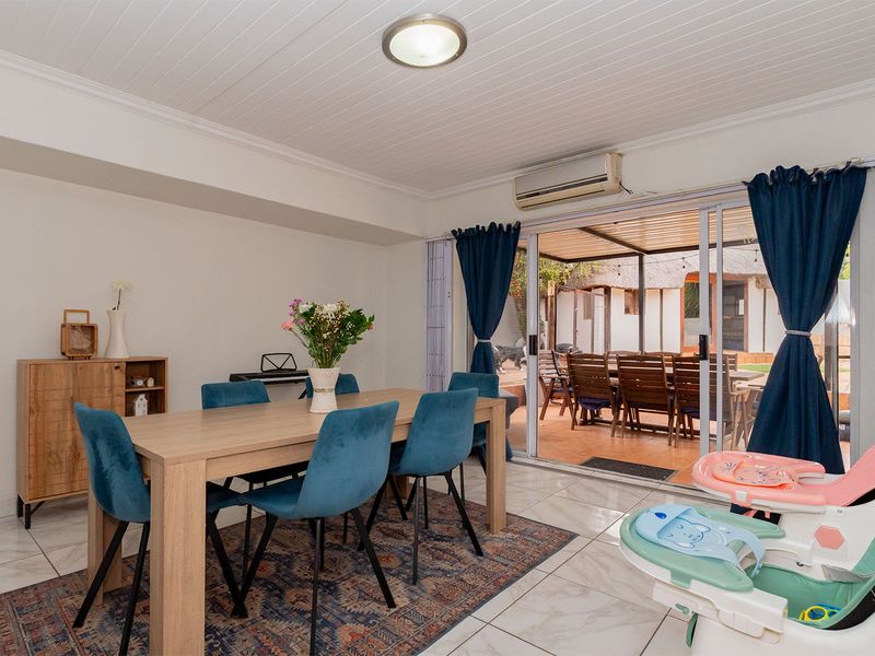 A bright dining area featuring tiled floors, coved ceilings, and large sliding glass doors that provide seamless access to the outdoor patio space.
