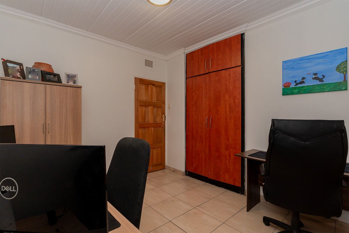A functional bedroom featuring tiled flooring, a tongue and groove ceiling, and a built-in wardrobe with wood-finish cabinetry.