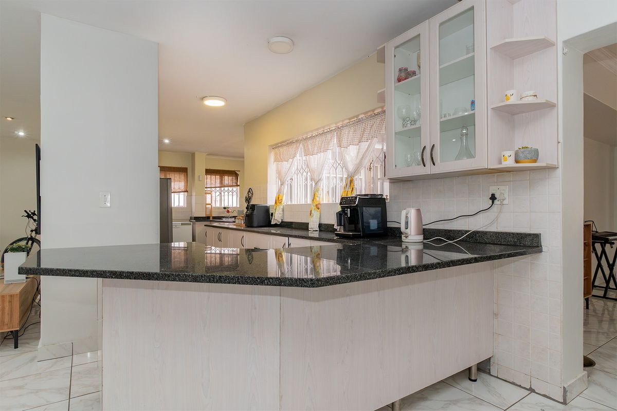 Functional kitchen featuring granite countertops, ample built-in cabinetry, and tiled flooring, offering a practical layout with a breakfast bar area.
