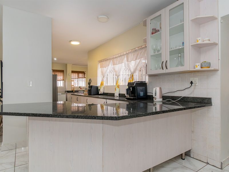 Functional kitchen featuring granite countertops, ample built-in cabinetry, and tiled flooring, offering a practical layout with a breakfast bar area.