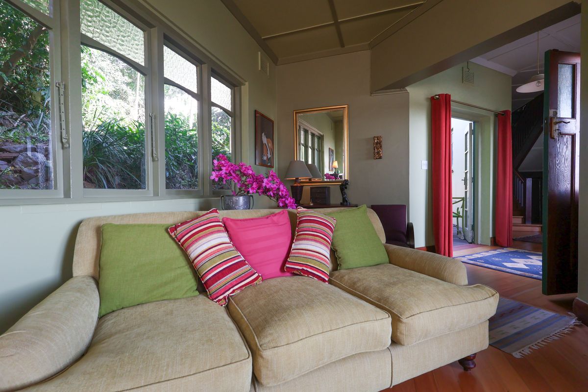 A cozy living room featuring timber flooring, classic casement windows, and a panelled ceiling, offering a warm and inviting atmosphere.