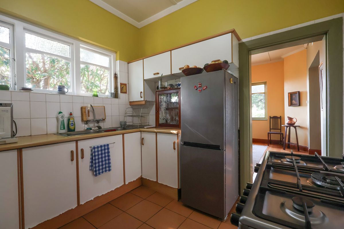 A dated kitchen featuring white cabinetry with worn edges, tiled backsplash, laminate countertops, and a gas hob, offering potential for modernization.