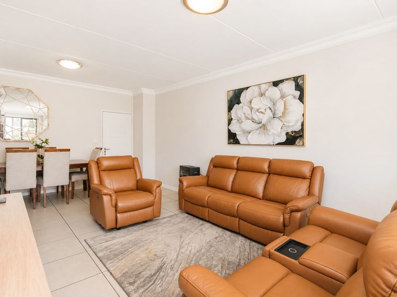 Spacious open-plan living and dining area featuring neutral tiled flooring, coved cornicing, and modern recessed ceiling lighting.