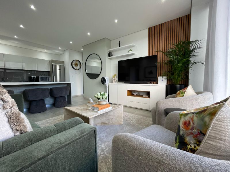 Modern open-plan living area featuring a sleek kitchen with island, timber slat feature wall, and recessed lighting, creating a cohesive and contemporary living space.