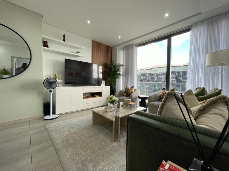 Modern living room featuring large sliding glass doors, built-in media cabinetry with timber slat detailing, recessed lighting, and neutral tiled flooring.